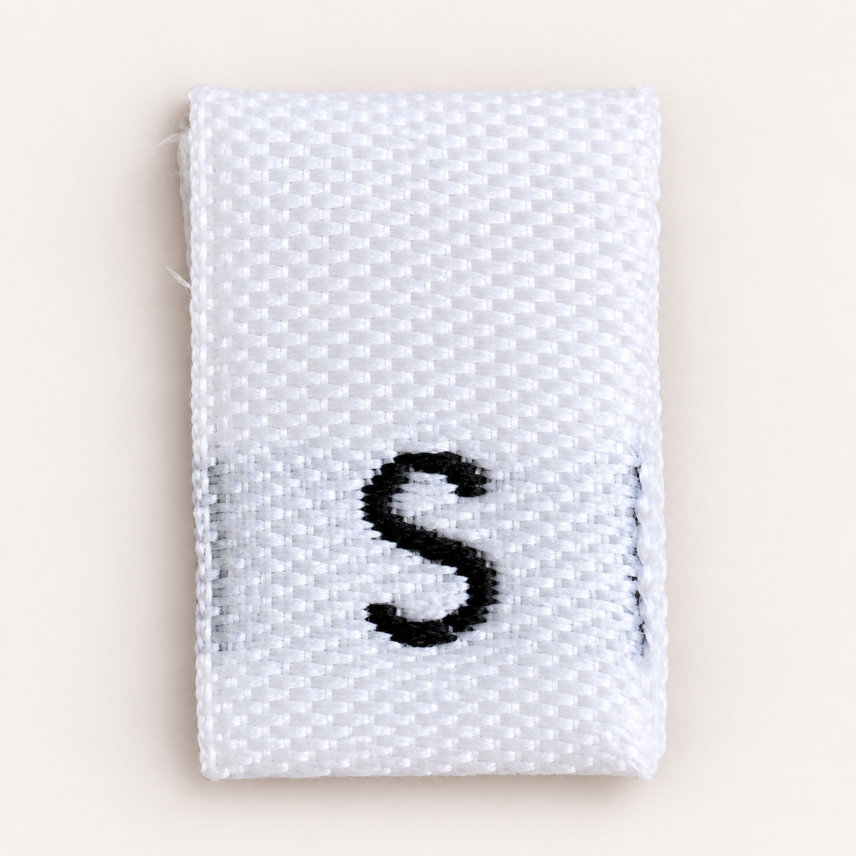 Close-up of a white woven size S clothing label with black lettering
