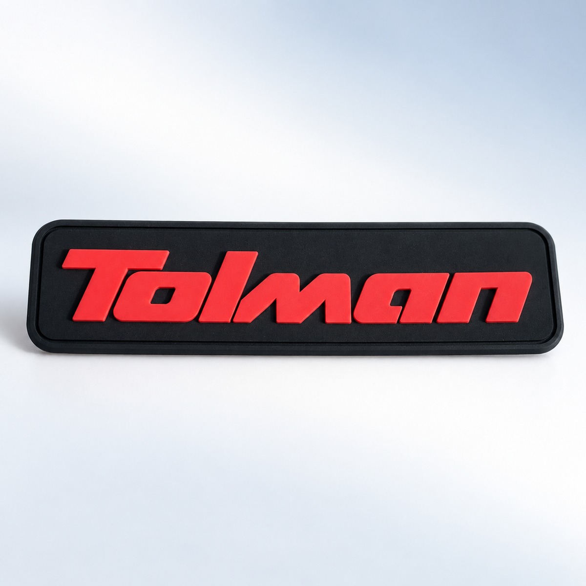 Black custom silicone label with raised red Tolman branding