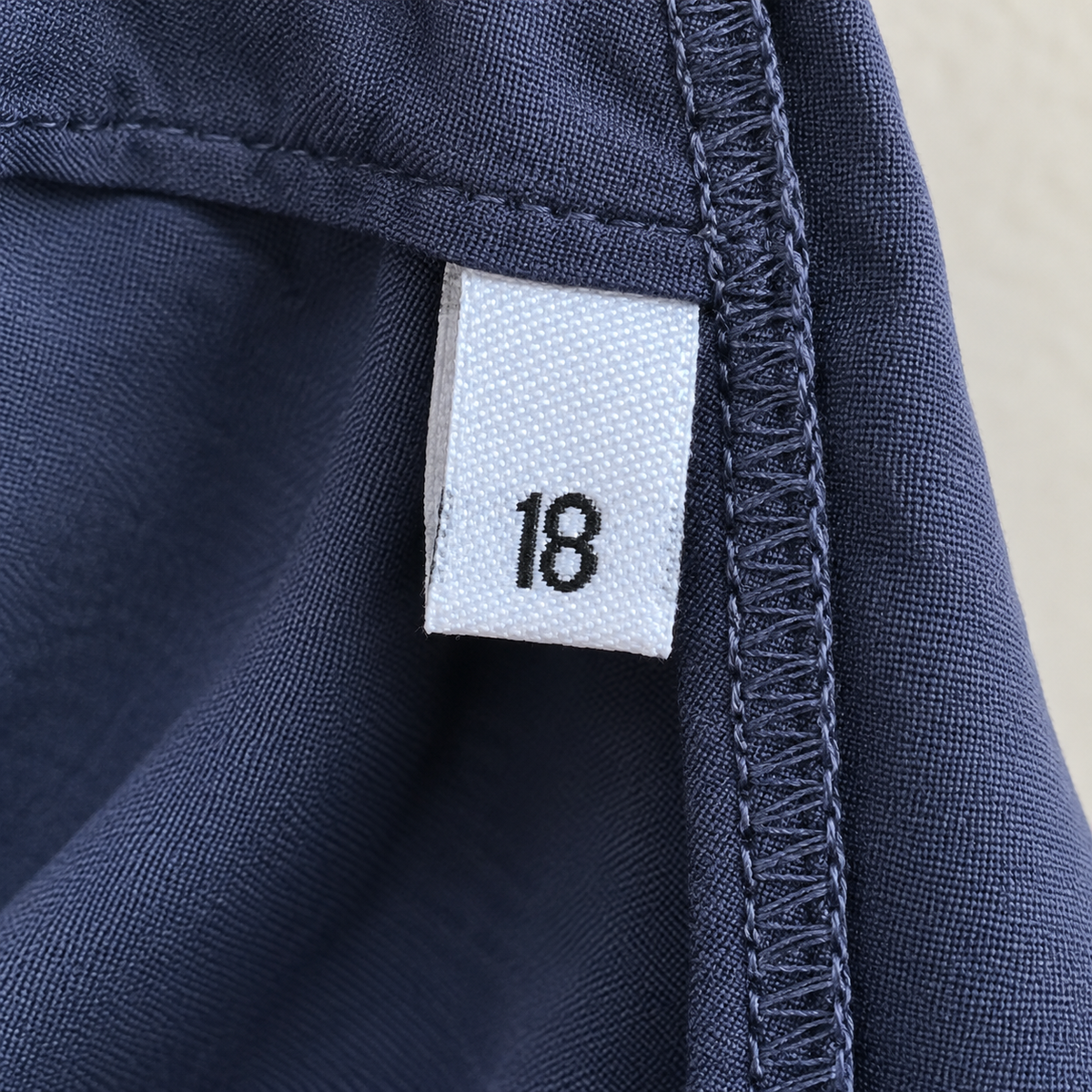 White women’s woven size 18 label sewn into the side seam of a navy garment