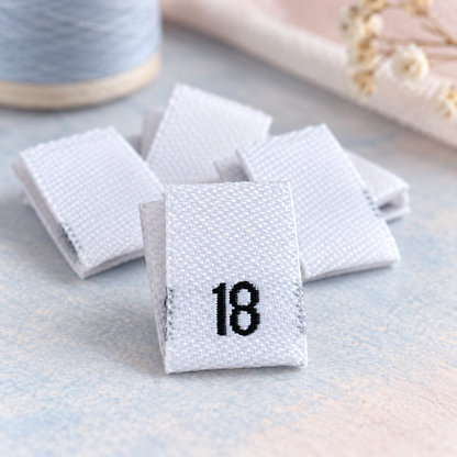 White women’s woven size 18 clothing labels on a soft blue and blush background