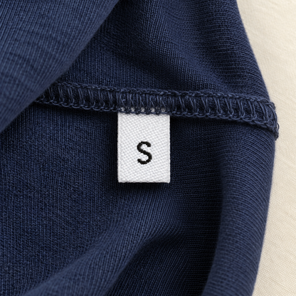 White woven size label with black S sewn into the side seam of a navy garment