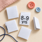 White 8–9 years kids’ woven clothing size label displayed with sewing thread and buttons