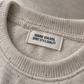 Personalised woven neck label sewn into the collar of a beige knitted sweatshirt