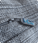 Custom silicone zipper pull branded Mact Marine attached to a grey textured bag