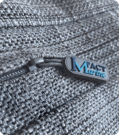 Custom silicone zipper pull branded Mact Marine attached to a grey textured bag