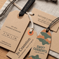 Assorted custom printed kraft swing tags with branded designs, eyelets and cord attachments