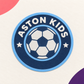 Thin round Aston Kids raised silicone football heat transfer badge in light and dark blue