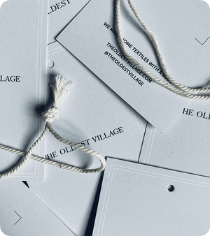 Close-up of custom printed grey silk swing tags with white string and black branding
