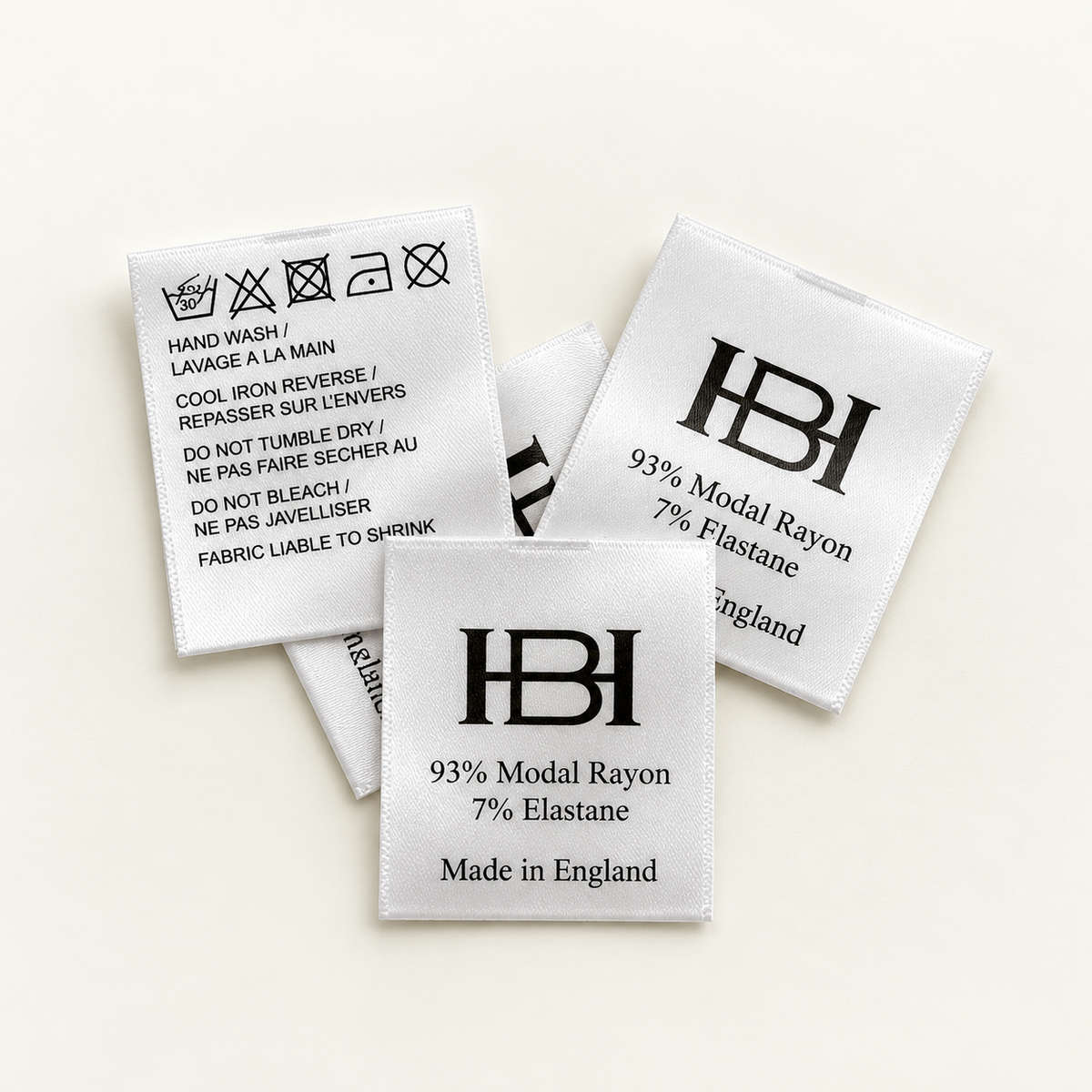 Custom printed satin care labels showing washing symbols, branding and fabric composition