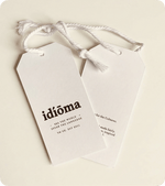 Two custom printed white silk swing tags with white cord on a cream background