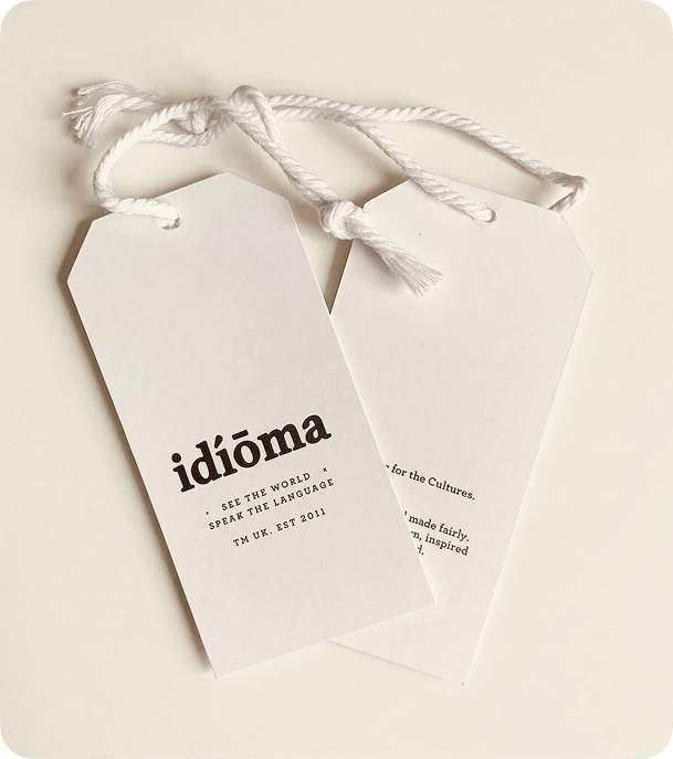 Two custom printed white silk swing tags with white cord on a cream background