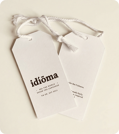 Two custom printed white silk swing tags with white cord on a cream background