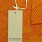 Custom recycled pulp swing tag with white cord attached to orange knitted clothing