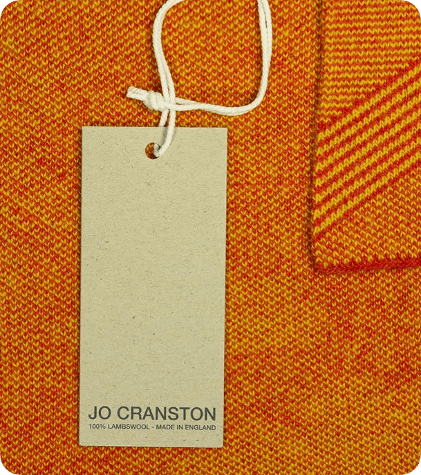 Custom recycled pulp swing tag with white cord attached to orange knitted clothing