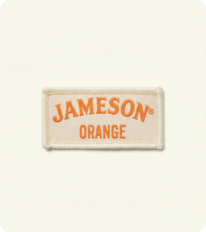 Custom cream woven fabric badge with orange Jameson lettering