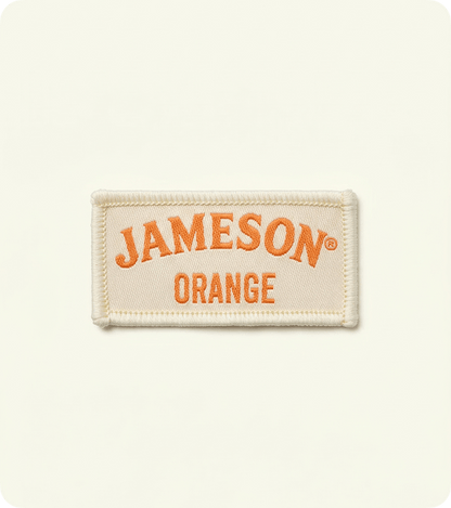 Custom cream woven fabric badge with orange Jameson lettering