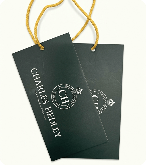 Two dark green custom printed silk swing tags with gold cord and white branding