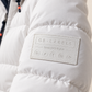 White custom leather GB Labels patch sewn onto the sleeve of a snow-white padded parka jacket